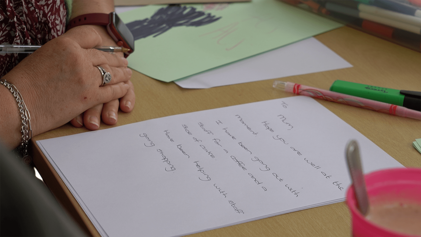 Julia supporting Ali to write a letter to his mum
