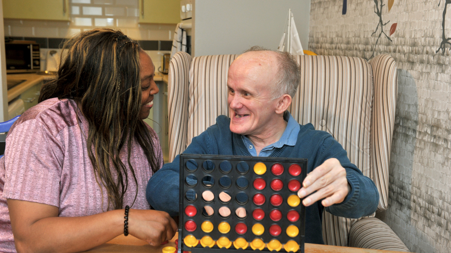 Support worker and person we support playing Connect4 together
