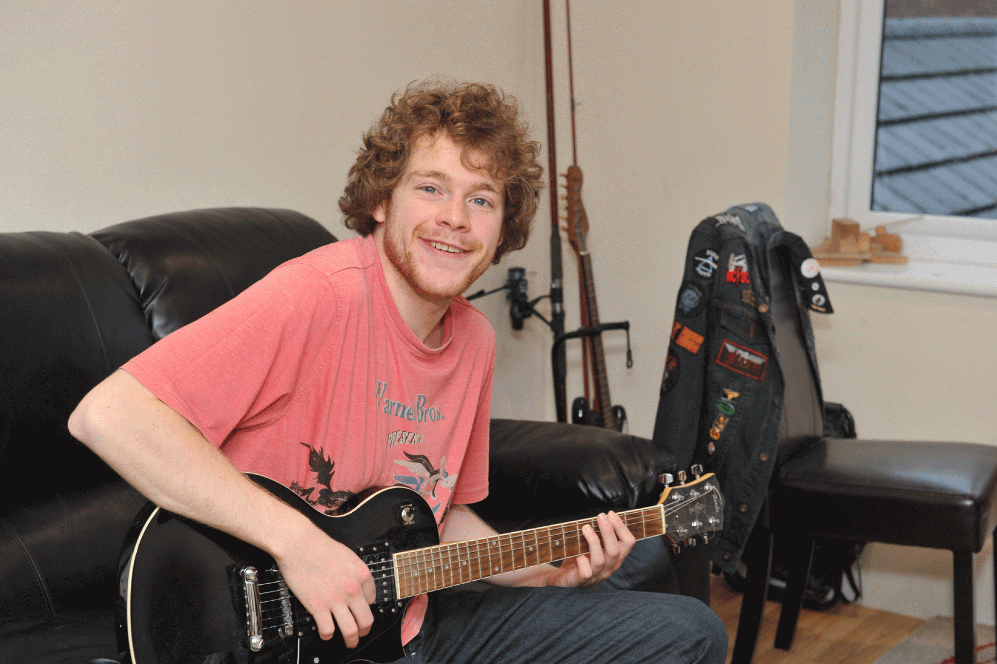 A man playing the guitar smiling at the camera