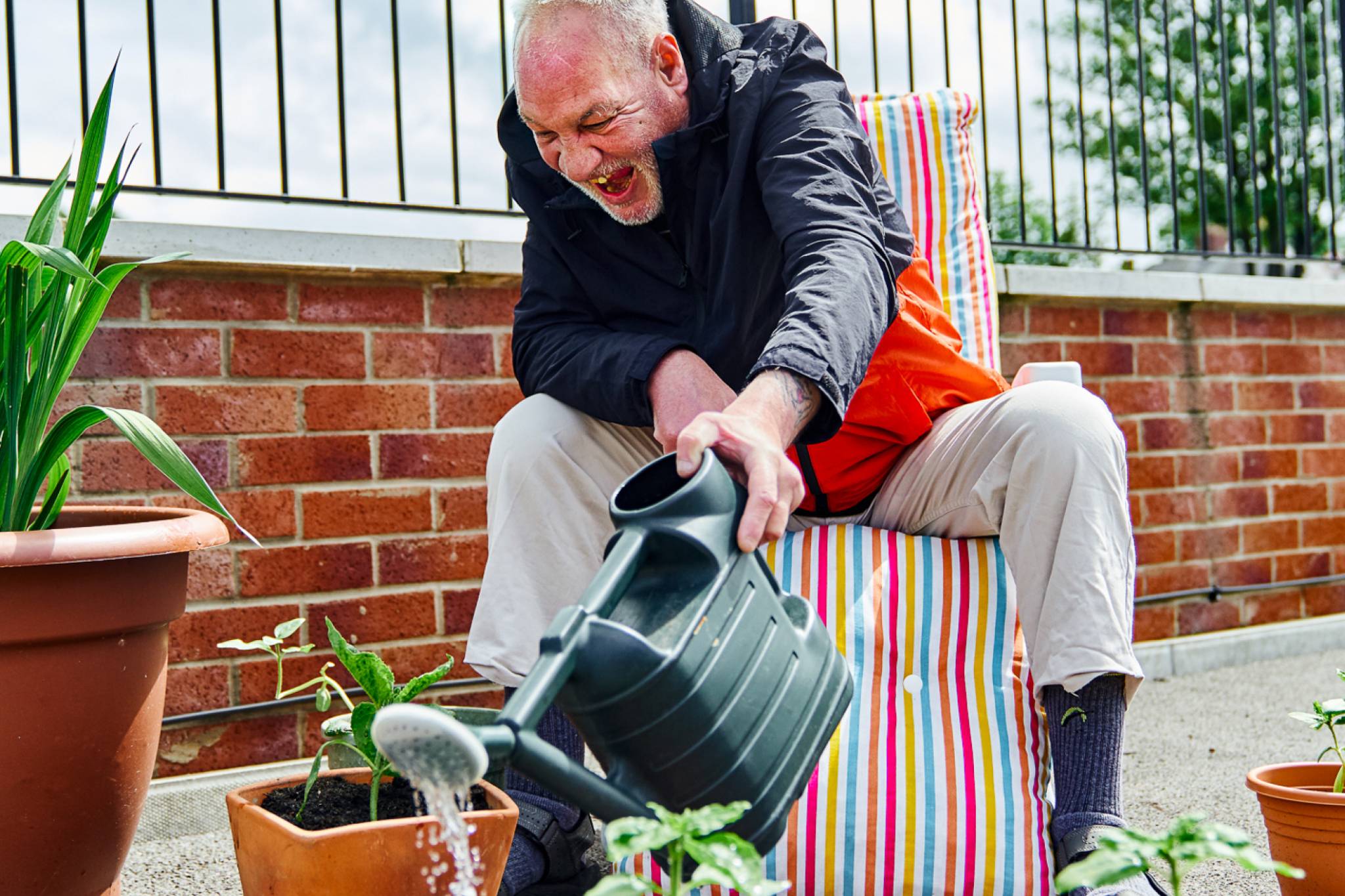 A man watering a potted plant