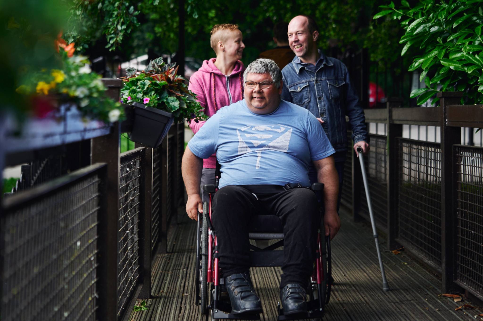 A man in a wheelchair and two people walking behind him