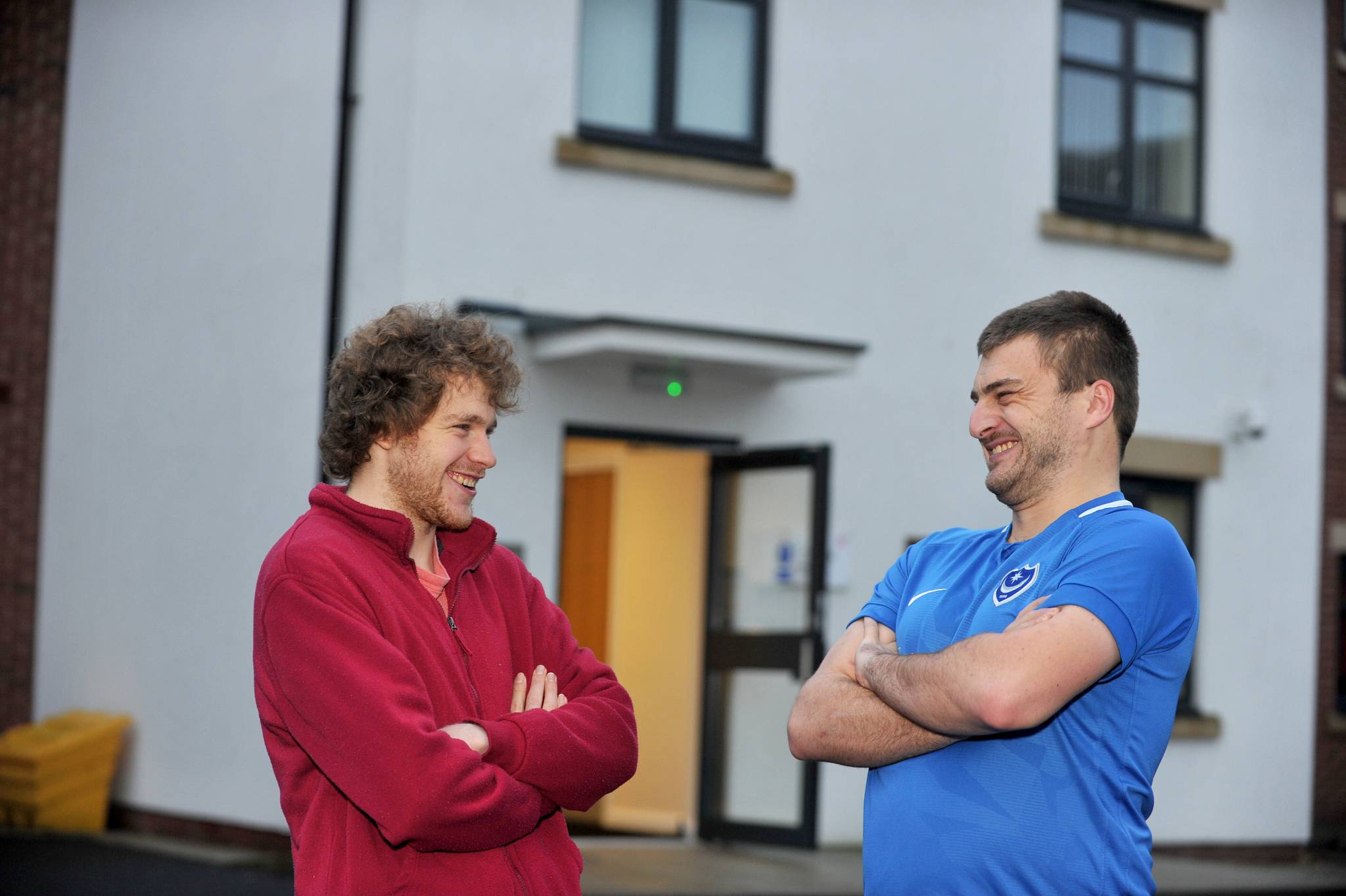 Two men stood talking in front of a white building